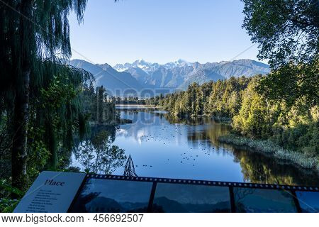 Perfect Reflection In Lake Matheson Surrounded By Beautiful Natural Forest Under Blue Sky With View 