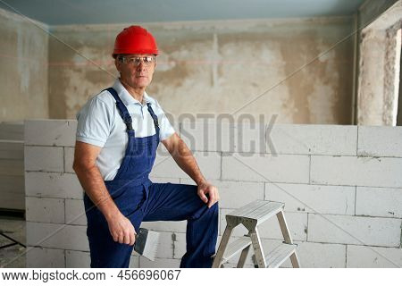 Professional Construction Worker In Uniform Standing With Spatula On Step Ladder. Portrait Of Contra