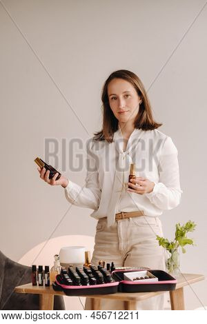 A Girl With A White Blouse Holds Bottles Of Essential Oils In Her Hands