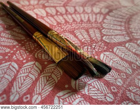 A Set Of Artists Brush On A Coloured Designed Tablecloth.