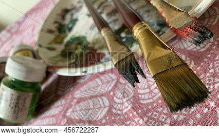 Artists Brushes Or Painting Brushes With Palatte And Colour Bottles In Blurred Background.