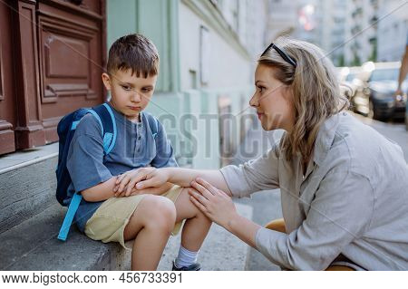 Mother Consoling Her Little Son On His First Day Of School, Sitting On Stair And Saying Goodbye Befo