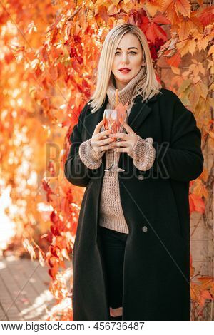 Glass With Cocktail Symbol Of Autumn Is Held In Hands Of Woman Of Model Appearance Elegantly Dressed