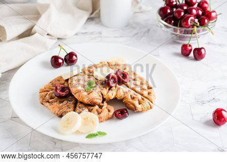 Appetizing Croffles With Cherries And Bananas On A Plate On The Table. Street Food. Homemade Breakfa