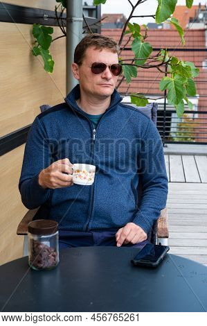 40 Year Old White Man With Sungasses, Drinking Coffee On The Terrace Of His Apartment, Brussels, Bel