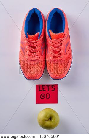 Vertical Shot Red Sneakers And Green Apple. Lets Go Inscription On Sticker Note. Isolated On White.