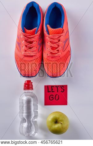 Vertical Shot Flat Lay Pair Of Shoes With Water Bottle And Green Apple. Sticker Note With Lets Go In