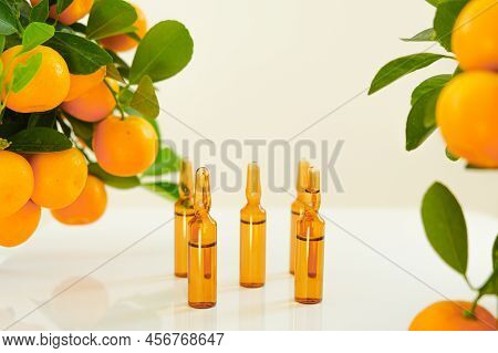 Vitamin C . Glass Ampoules With A Solution Of Vitamin C And Tangerine Bushes On A Light Background.b