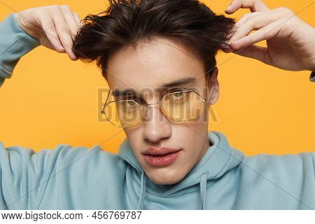 A Close Portrait Of A Funny Man Standing On An Orange Background In Bright Sunglasses Looking At The