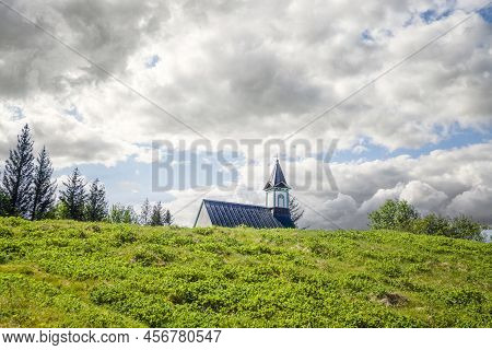 Small Church In A Rural Scenery In Cloudy Weather On A Green Meadow