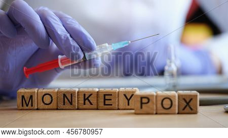 Close-up Of Words Monkey Pox Collected Of Wooden Cubes. Nurse Holding Injection Syringe In Hand. Vir