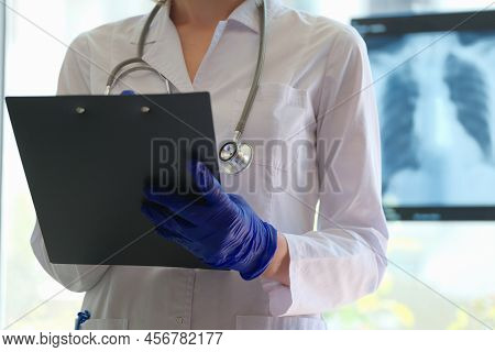 Close-up Of Doctor Pulmonologist Holding Clipboard And Filling Form Of Patient. Radiologist Or Pulmo