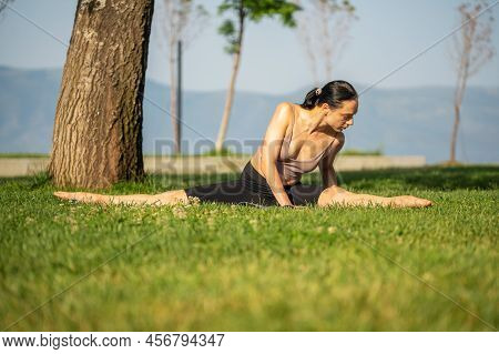 A Woman In Brown Sport Bra And Black Short Sitting On Yoga Mat Doing Maditation With Hand Together A