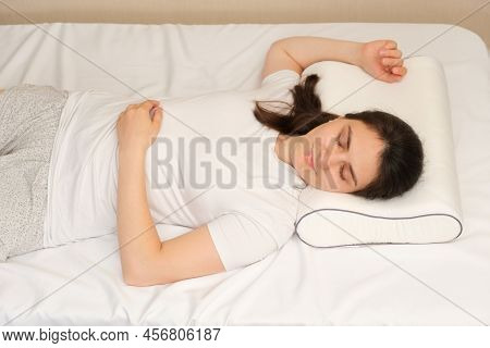 A Woman Sleeps On An Orthopedic Pillow Made Of Memory Foam, Lying On A Bed. The Correct Pillow For A