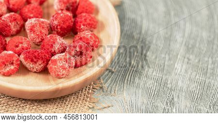 Frozen Raspberry On Wooden Plate On Wooden Backdrop Close Up. Copy Space. Selective Focus.
