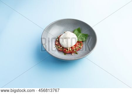 Buratta Cheese And Tomatoes In A Bowl. Decorated With Pine Nuts. Selective Focus.