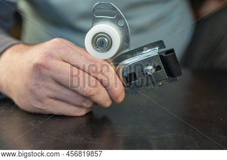 A Grown Man Is Holding A Set Of Furniture Fittings In His Hands. Top Roller Mount For Sliding Closet