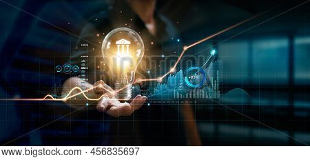 Businessman Holding Creative Light Bulb With Growth Graph And Banking Icons. Financial Innovation Te