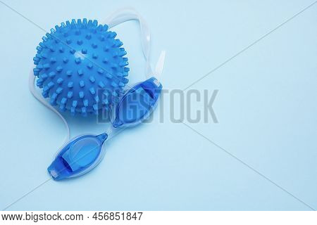 Swimming Goggles And A Ball For Playing In The Water On A Blue Background With Copy Space