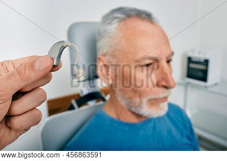 Audiologist Presents Bte Hearing Aid For Mature Hearing Impaired Man To Treat His Deafness, Close-up