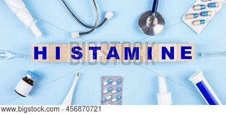 On A Blue Background, A Stethoscope, A Thermometer, Other Medicines And Wooden Cubes With The Text H
