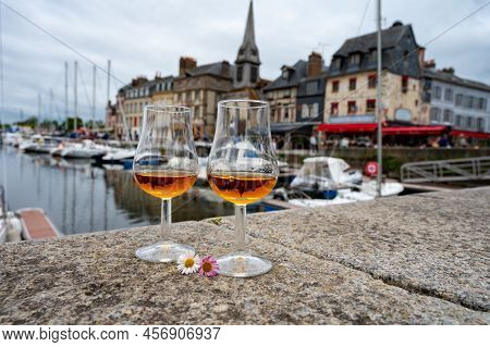 Tasting Of Apple Calvados Drink In Old Honfleur Harbour With Boats And Old Houses On Background, Nor
