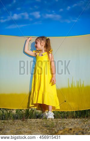 Ukrainian Girl 7 Years Old, She Is A Patriot Of Ukraine, Dressed In A Yellow Dress Against A Blue Sk