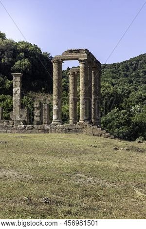 Vertical View Of Close Up Roman Temple Under Blue Sky And Green Vegetation In The Background