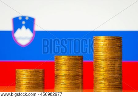 Coins Stacks Forming Increasing Graph On The Background Of Slovenia Flag. Financial Development Of T