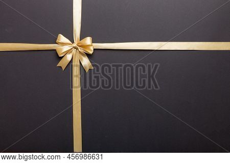 Top View Of Gold Ribbon Rolled And Yellowbow Isolated On Colored Background. Flat Lay With Copy Spac