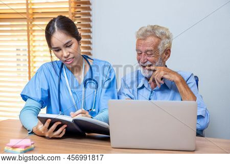 Nurse Helping Patient For Reading Note Book. Woman Helping Senior Man Read Note Book