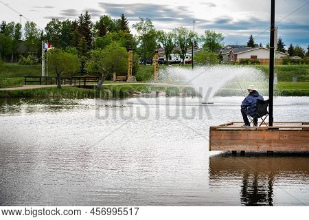 Airdrie Alberta Canada, June 12 2022: An Elderly Person Fishing At A Stocked Rainbow Trout Pond At N