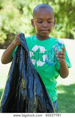 Little boy in recycling tshirt picking up trash on a sunny day