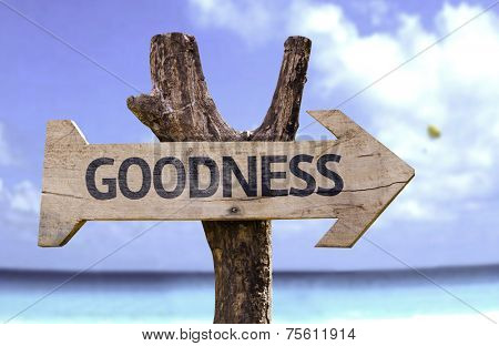 Goodness wooden sign with a beach on background