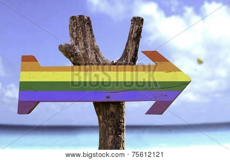 Rainbow wooden sign with a beach on background