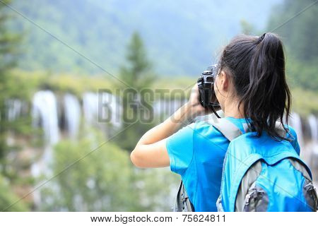 woman tourist/photographe taking photo with digital camera in jiuzhaigou national park,china