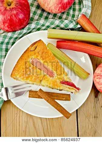 Pie with apple and rhubarb in plate on wooden board