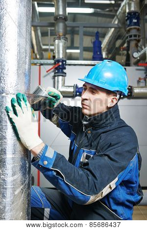industrial construction worker at boiler room pipe heat insulation work