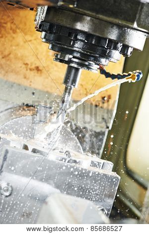 End-tooth vertical mill cutting the metal blank with cooling liquid