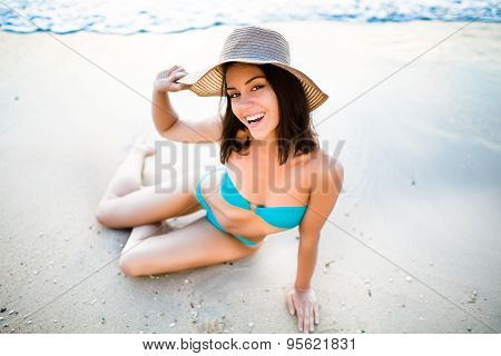 Beautiful brunette woman sitting on sandy beach and smiling, Having fun on holiday vacation