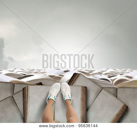 Close up of woman legs standing on the edge of rock of books 