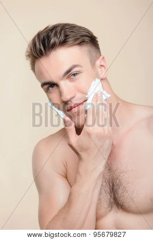 Topless man applying mean of shaving on face