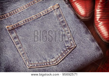 Closeup of a pair of blue jeans and cowboy boots with a faded retro look. 