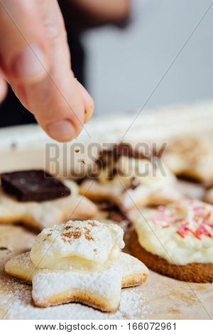 Hand of person putting a few cinnamon powder at the top of the cookie.