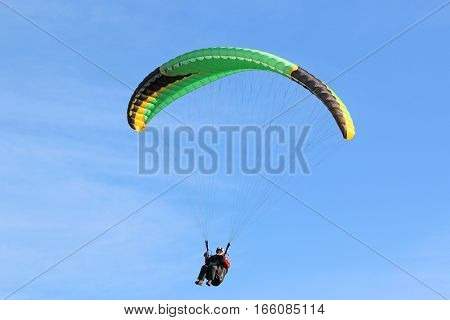 Paraglider under his wing in a blue sky