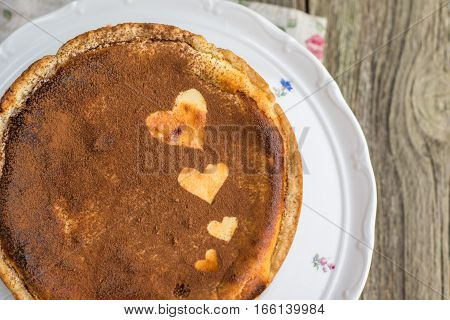 Detailed Top View On Baked Cheesecake Sprinkled With Cocoa With Heart Shapes On Cake Serving Platter