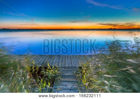 Long Exposure Image Of Blue  Sunset Over A Jetty On The Shore Of A Lake