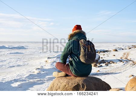 Meditation concept. Man have relax after hard jorney. Guy look far to the horizon. Open space. Free place for advertising travel goods or tourism stuff. Winter landscape with frozen sea.