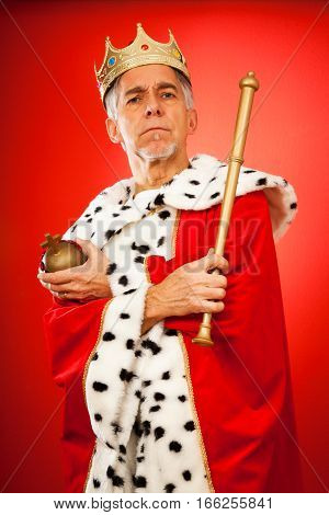senior man wearing a king's attire, looking serious