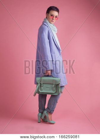 Portrait of a girl in a purple coat on a gtay background in pastel colors